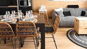A modern interior with a dining area, black cabinets, a gray sofa, and a mountain landscape painting. - The Marmots' Nest • Mountain View • 6 people (Orcières)