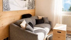 A cozy room with a sofa, a wooden cabinet, and a large mountain landscape painting. - The Marmots' Nest • Mountain View • 6 people (Orcières)