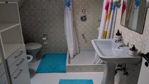Uma casa de banho com sanita, chuveiro, banheira e lavatório.