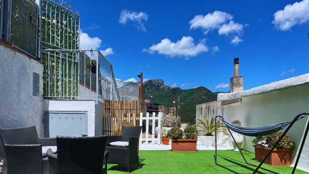 A rooftop terrace with artificial grass, wicker furniture, potted plants, and a hammock. - Casa Tasca, a cozy and quiet apartment with a large terrace. (Ravello)