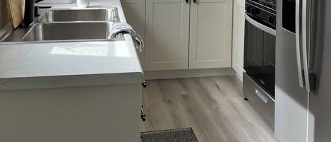 Una cocina moderna con armarios blancos, electrodomésticos de acero inoxidable, una ventana y una estufa empotrada.
