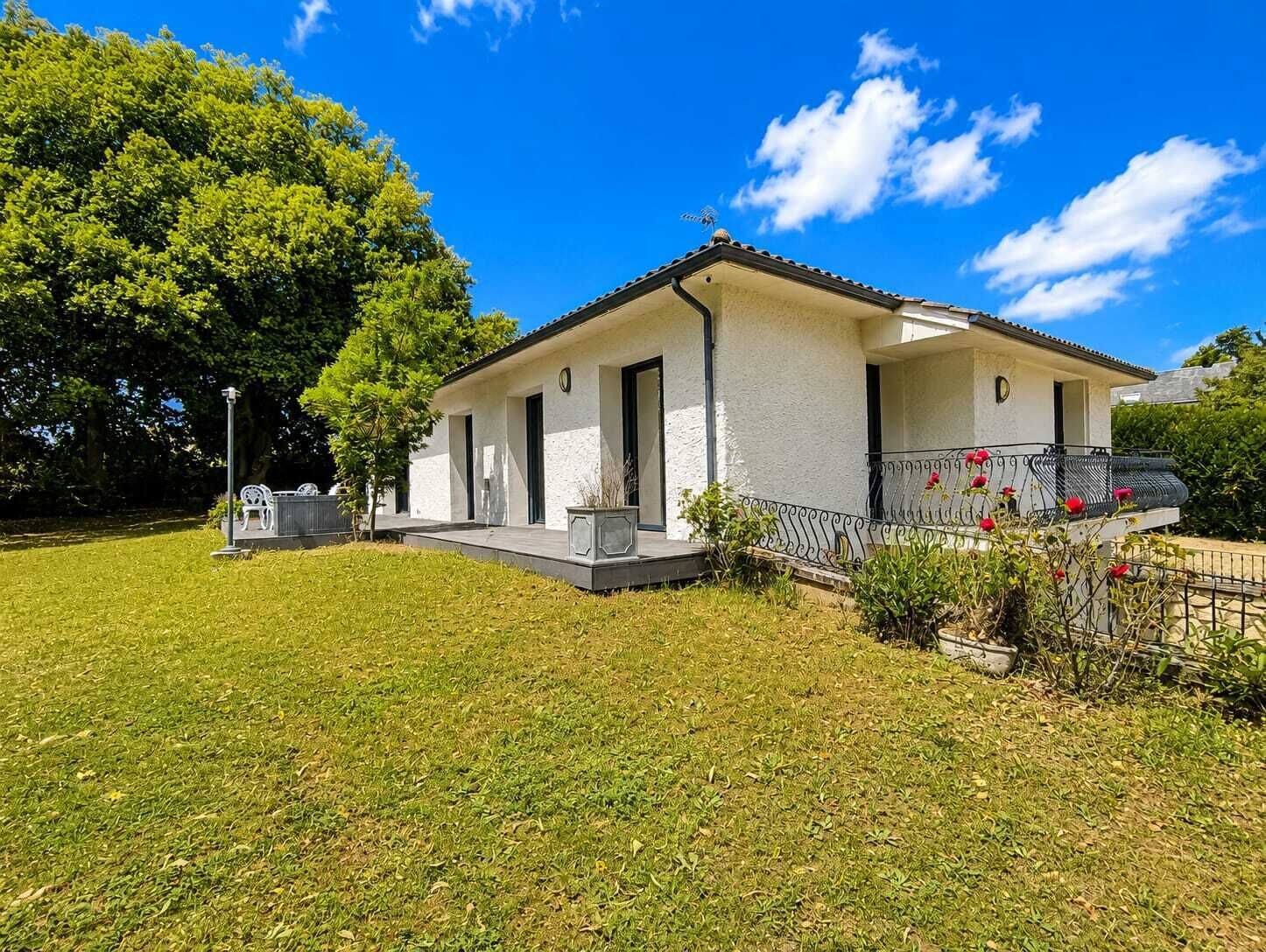 A single-story house with a flat roof, a front porch, and a small garden.