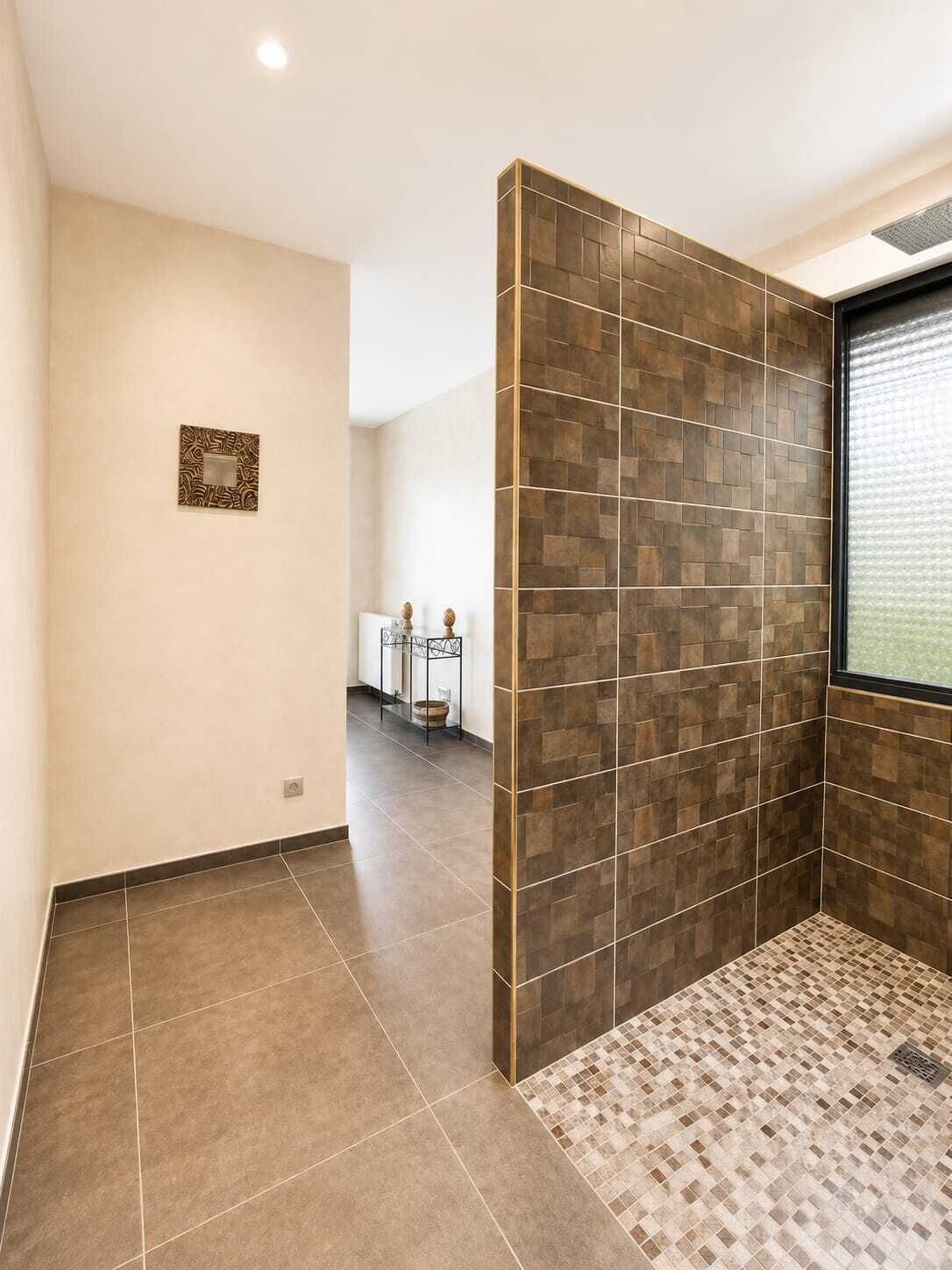 Une salle de bain moderne avec un carrelage au sol, un espace douche et une fenêtre équipée de stores.