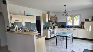 Une cuisine moderne avec un îlot central, des chaises transparentes et un chien allongé sur le sol.