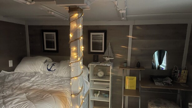 Een slaapkamer met twee bedden, een wandplank, een klein tafeltje, een klok en een spiegel.