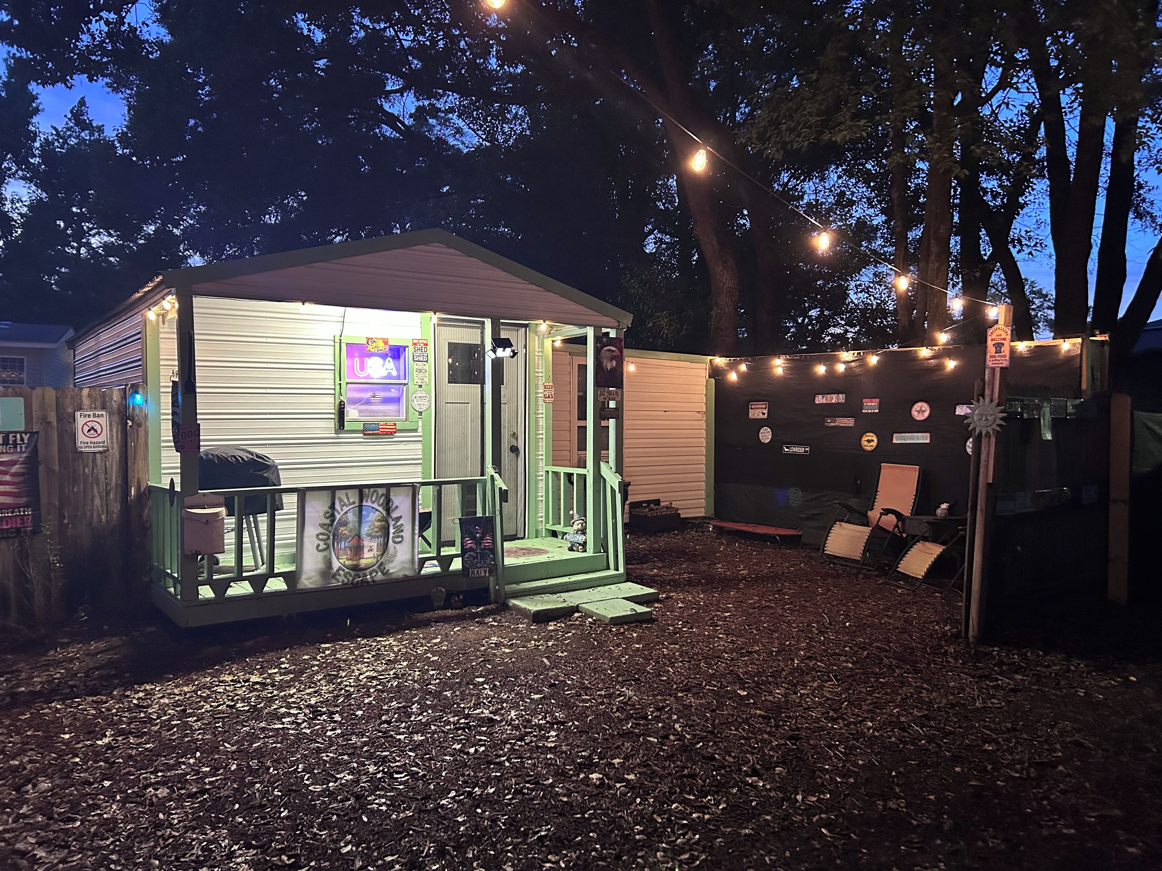 A small, illuminated structure with a signboard, a fire ban sign, and a welcome sign.