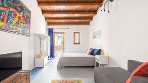 A room with a bed, a sofa, a TV, and a colorful rug. - Blue home in Vucciria (PALERMO)
