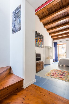 A staircase leading to a room with a television, a patterned rug, and a wooden ceiling. - Blue home in Vucciria (PALERMO)