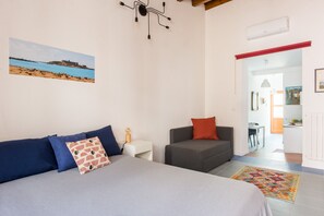 Ein Schlafzimmer mit einem Bett, einem Sessel, einem kleinen Tisch und einem Bild an der Wand.