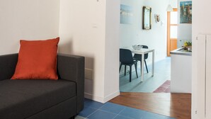 A modern living room with a grey sofa, a colorful rug, and a red pillow. - Blue home in Vucciria (PALERMO)