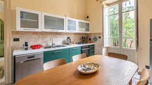 A kitchen with a wooden table, green cabinets, and a window with a view of greenery. - Zisa Gardens of Palermo (PALERMO)