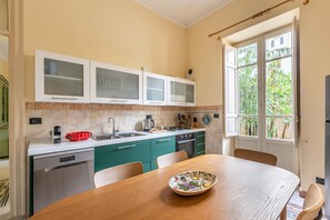 A kitchen with a wooden table, green cabinets, and a window with a view of greenery. - Zisa Gardens of Palermo (PALERMO)