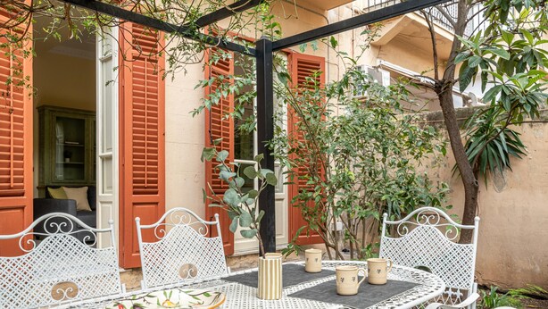 A white metal table with chairs, a potted plant, and a bowl of fruit. - Zisa Gardens of Palermo (PALERMO)