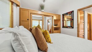 A bedroom with a bed, pillows, a mirror, a ceiling fan, and wooden furniture. - Lake Sutherland Tiny Home, Heaven (Port Angeles)