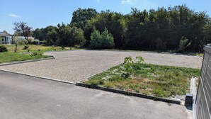 Un estacionamiento con zona de grava y parche de césped con pequeñas plantas.