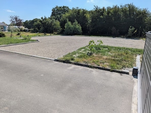 Un estacionamiento con zona de grava y parche de césped con pequeñas plantas.