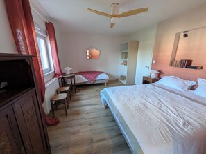 A bedroom with a bed, a desk, a chair, a wardrobe, a ceiling fan, and a window with curtains. - Maison Millefeuille (Saint-Hilaire-de-Riez)