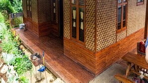 Una casa de madera con techo de lámina corrugada, un porche y un pequeño jardín.