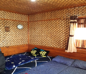 Ein Zimmer mit Wandmuster, einem Bett mit einer decke mit Sternenmuster, einer Uhr und einem Fenster mit Vorhängen.