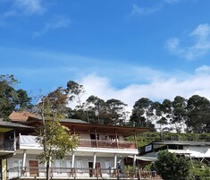 A two-story building with balconies, surrounded by trees and a clear sky.