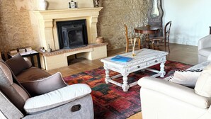 Ein gemütliches Wohnzimmer mit Kamin, Steinwänden und Holzbalken.