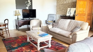 Ein Wohnzimmer mit Sofa, Sesseln, Couchtisch und Fernseher.