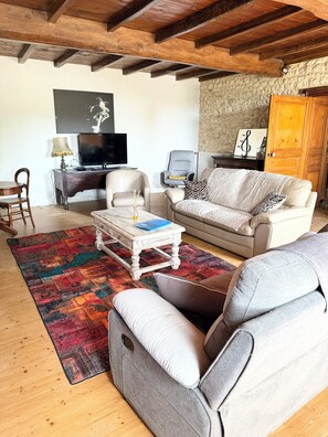 Ein Wohnzimmer mit Sofa, Sesseln, Couchtisch und Fernseher.