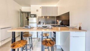 A modern kitchen with a central island, bar stools, and a microwave. - Fabregas - Proche plage - Petfriendly (La Seyne-sur-Mer)