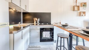 A modern kitchen with stainless steel appliances, a wooden island, and bar stools. - Fabregas - Proche plage - Petfriendly (La Seyne-sur-Mer)