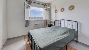 A bedroom with a bed, a window with curtains, a radiator, and decorative wall art. - Fabregas - Proche plage - Petfriendly (La Seyne-sur-Mer)