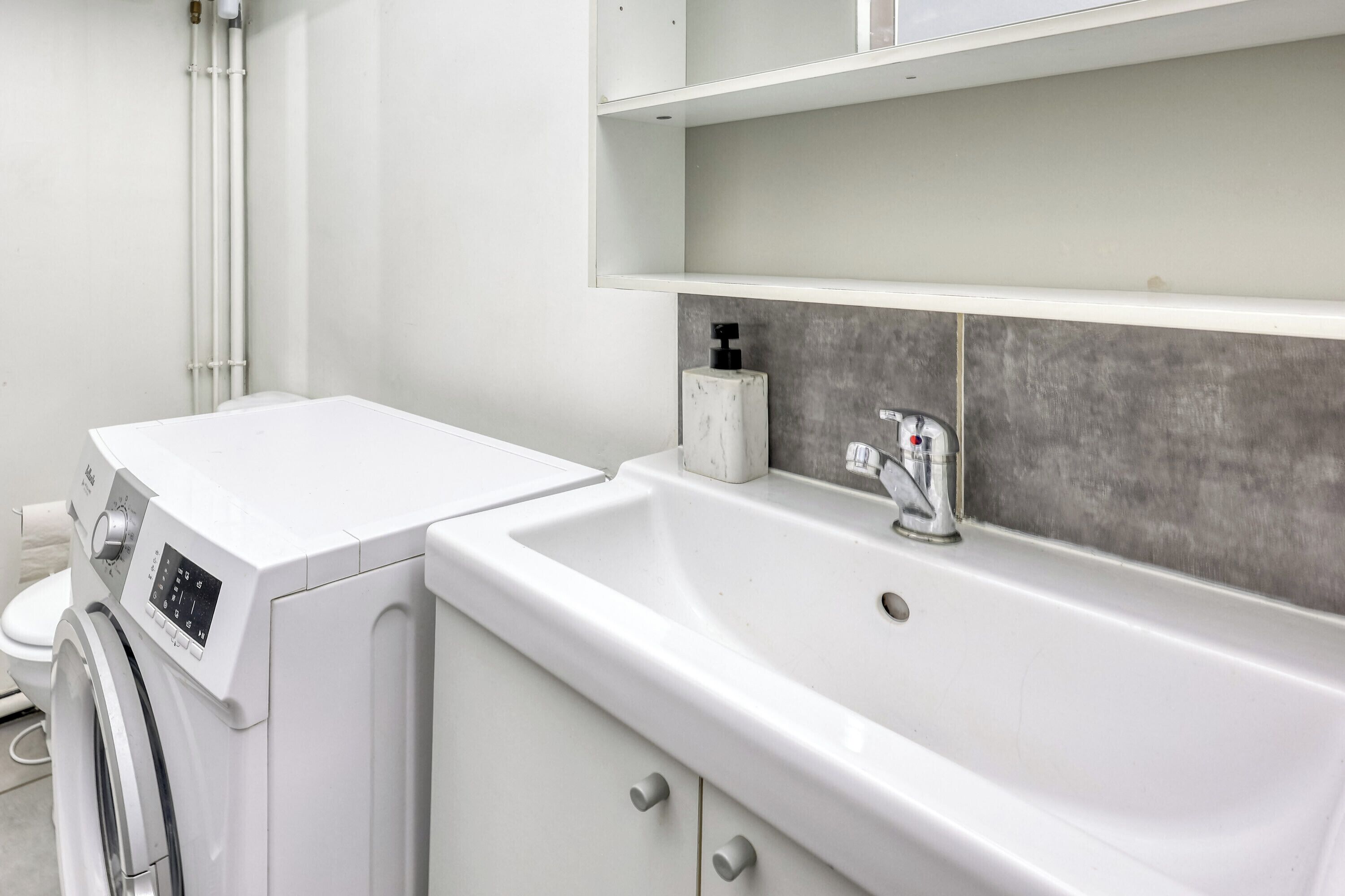 Ein modernes Badezimmer mit Waschmaschine, Waschbecken und Toilette.