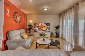 Ein Wohnzimmer mit einer Couch, einem Couchtisch, einem Fernseher und einem Kamin.