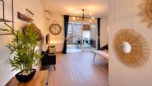 A modern living space with a potted plant, a wall clock, and a dining area with a table and chairs. - Petit Duc - AC - Patio - Wifi (Saint-Paul)