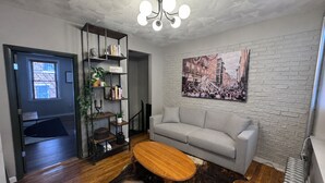 A modern living room with a sofa, a coffee table, a bookshelf, and a cityscape painting on the wall. - Family-friendly 4-bedroom apartment in the historic North End of Boston (Boston)
