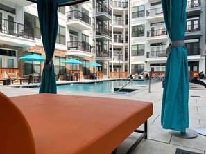 A poolside area with lounge chairs, umbrellas, and a view of a multi-story building with balconies. - 1BR w/ Balcony Steps to Broadway Nashville (Nashville)