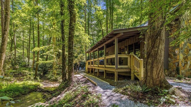 Une cabane en bois située dans une forêt, avec un chemin de gravier menant à celle-ci.