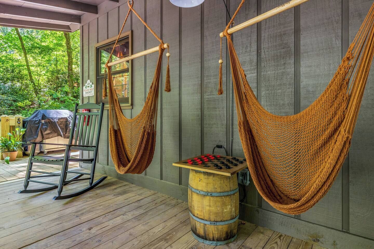 Un fauteuil en forme de hamac, un tonneau en bois et un jeu d’échecs sur une terrasse en bois.