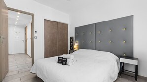 Et moderne hotelværelse med en stor seng, et sengebord, et garderobeskab og en dør til et badeværelse.