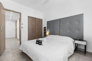 Une chambre d’hôtel moderne, dotée d’un grand lit, d’une table de chevet, d’une armoire et d’une porte donnant accès à la salle de bain.