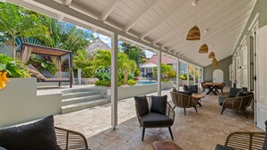 Un patio al aire libre con mobiliario de mimbre, una piscina y un paseo cubierto.
