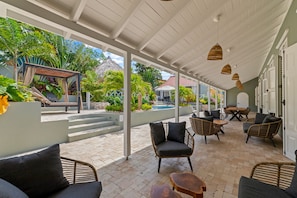 An outdoor patio with wicker furniture, a pool, and a covered walkway.