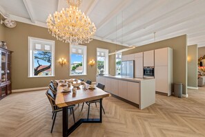 Eine moderne Küche mit Kochinsel, Pendelleuchten und einem Essbereich mit Holztisch und Stühlen.