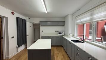 A modern kitchen with a central island, grey cabinets, a microwave, and a window with a view.