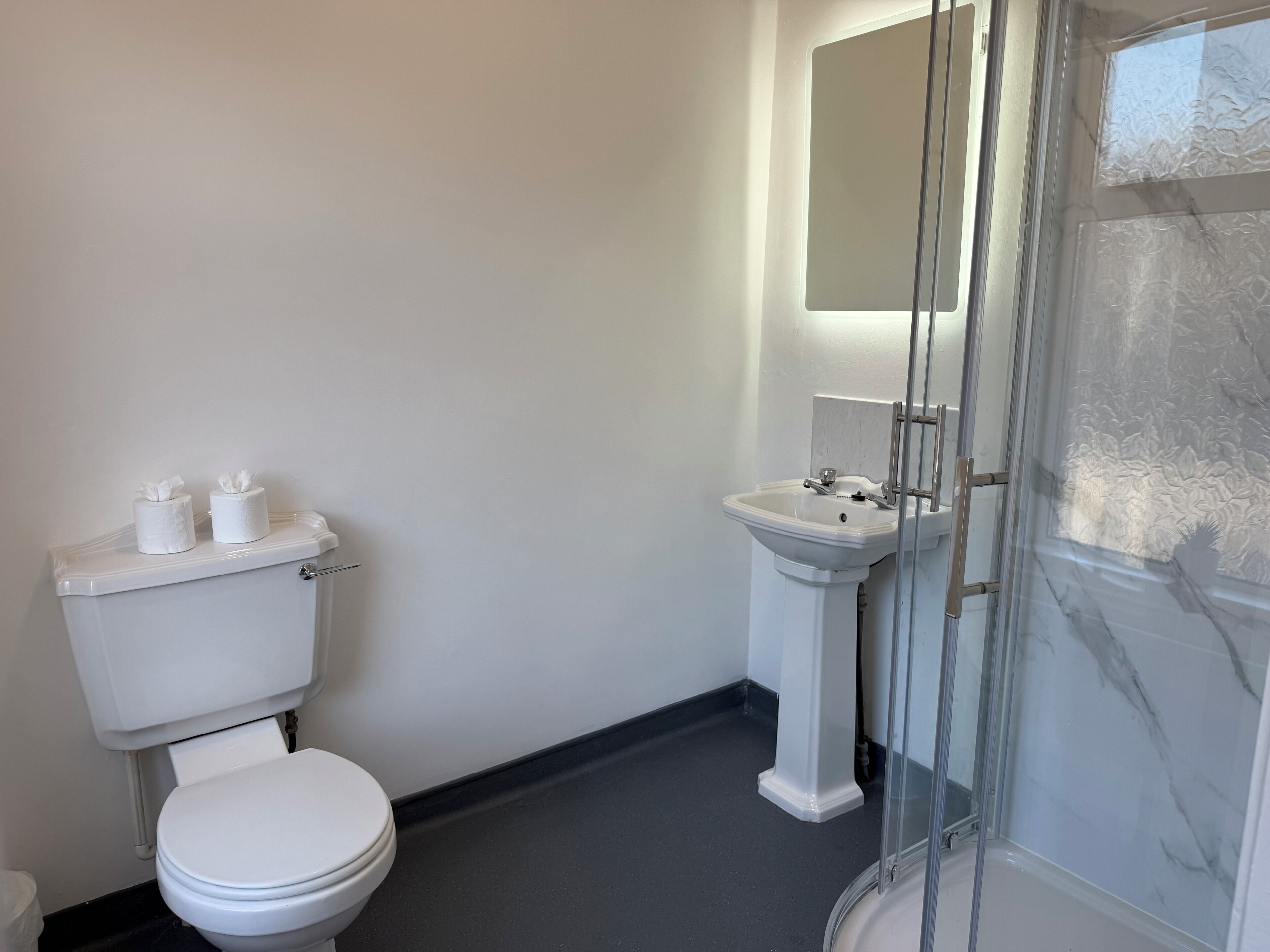Un baño con inodoro, lavabo y cabina de ducha de vidrio.