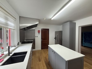 Una cocina moderna con armarios blancos, campana extractora de acero inoxidable, horno empotrado y refrigerador.
