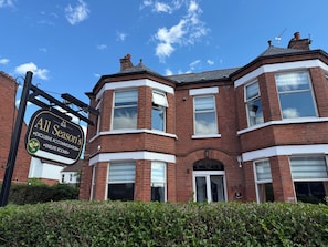 A corner building with a sign for 'All Season's Exclusive Accommodation ENSuite Rooms.'