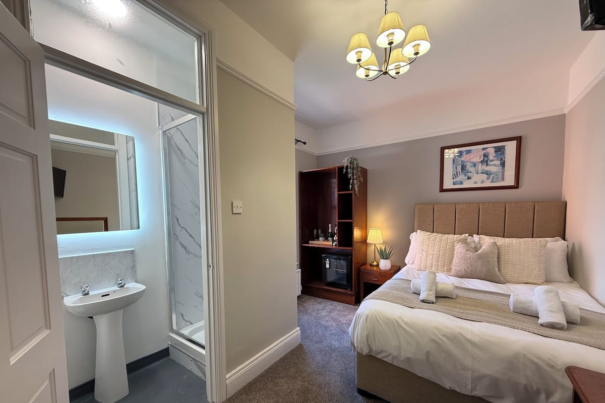 A hotel room with a bed, bedside lamp, and a large mirror.