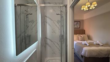 Un baño con ducha de vidrio, lavamanos blanco y bañera.