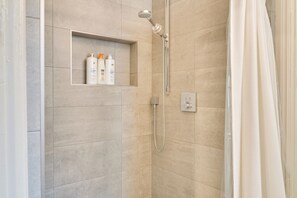 A shower with a handheld showerhead, a built-in shelf with toiletries, and a shower control panel. - Walkable to everything in Santa Cruz: Pet and Kid-Friendly (Santa Cruz)