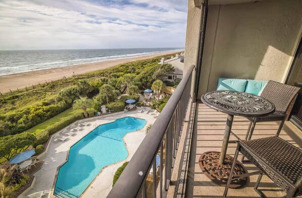 Ein Balkon mit Blick auf den Strand und ein Schwimmbecken.